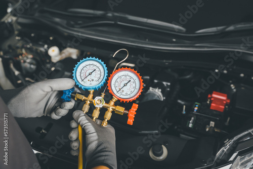 Hand of car mechanic technician use meter to check car air conditioner system heat problem and fix repairing and filling air refrigerant.