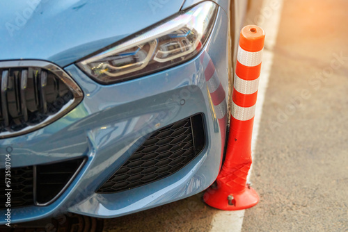 Car and broken flexible orange parking bollard, selective focus. Car hit bollard, damaged driver side bumper. Bumper posts are made to absorb collision impact with minimal damage while parking