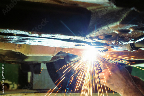 Canvas Print Car mechanic welds car exhaust pipe mount by semi-automatic welding