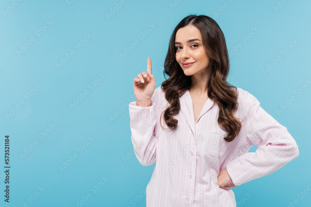 brunette young woman in sleepwear showing idea sign isolated on blue. brunette young woman in sleepwear showing idea sign isolated on blue.