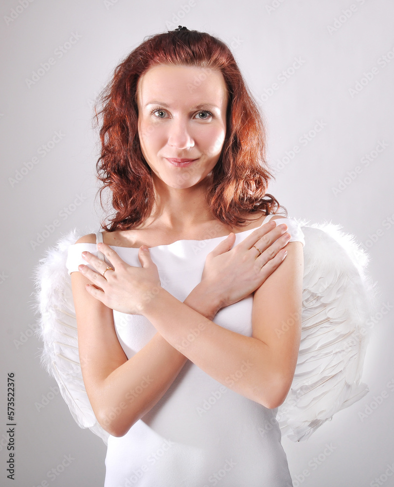 Funny, mischievous, naughty angel. Redhead woman in studio with white wings. White angel Funny, mischievous, naughty angel. Redhead woman in studio with white wings. White angel