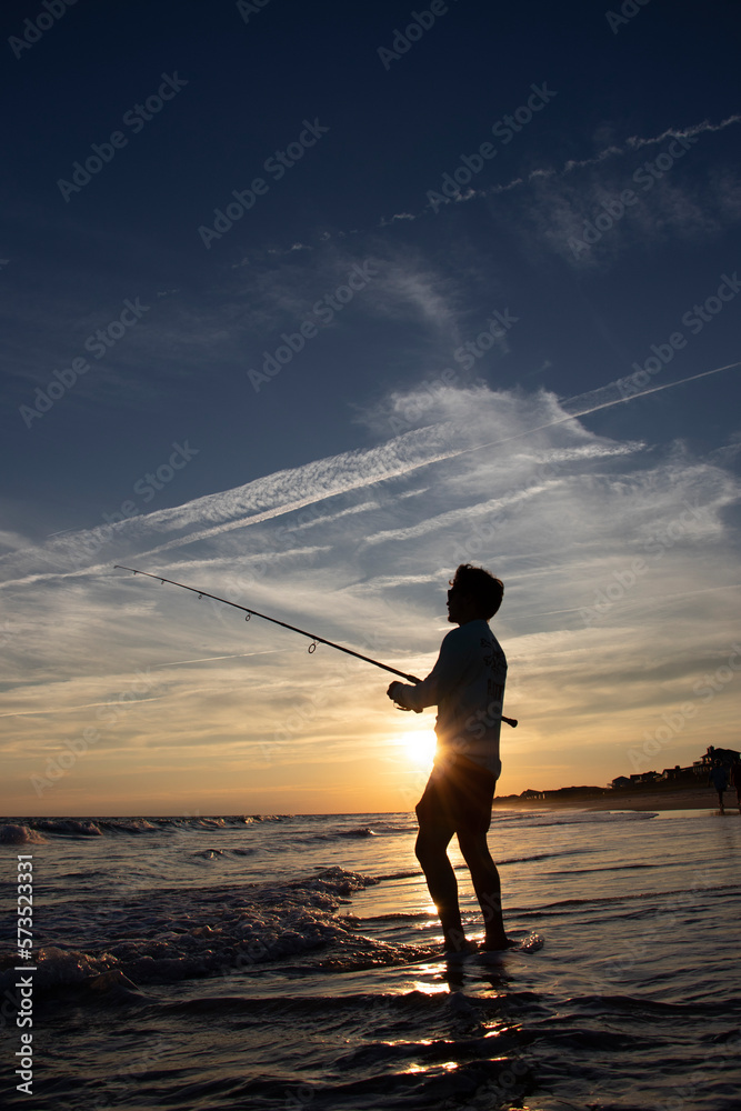Fisherman surf fishing at sunset.