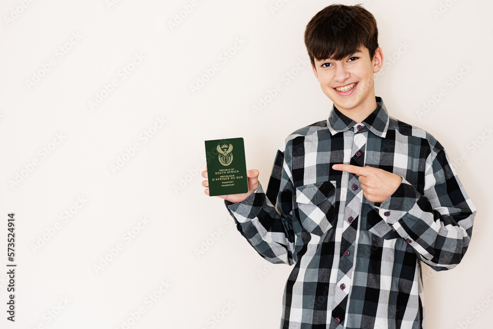 Young teenager boy holding South Africa passport looking positive and happy standing and smiling with a confident smile against white background. Young teenager boy holding South Africa passport looking positive and happy standing and smiling with a confident smile against white background.