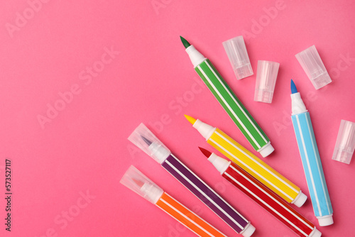 Many bright markers on pink background, flat lay. Space for text