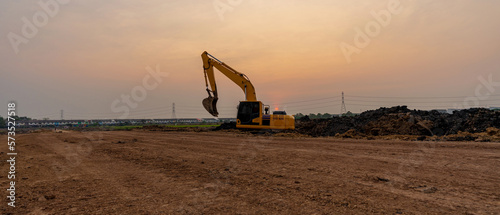 Excavator working on construction site at sunset background