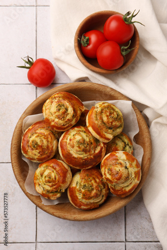 Fresh delicious puff pastry with tasty filling and tomatoes on white tiled surface, flat lay