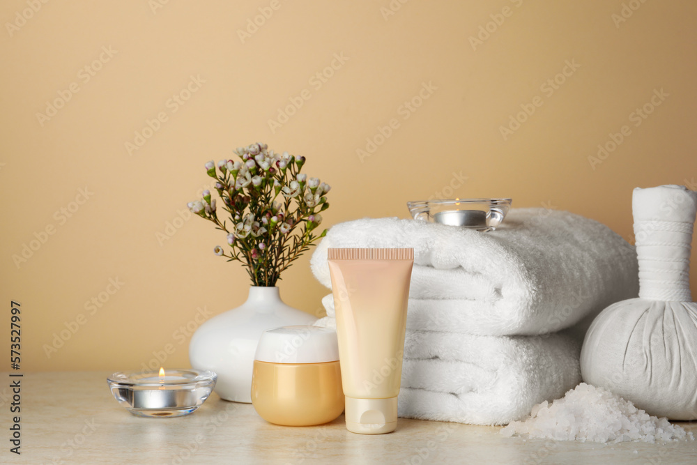 Composition with different spa products, candles and flowers on beige table. Space for text Composition with different spa products, candles and flowers on beige table. Space for text