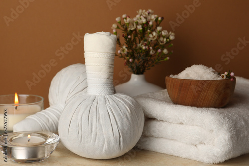 Composition with different spa products  candles and flowers on beige table against brown background