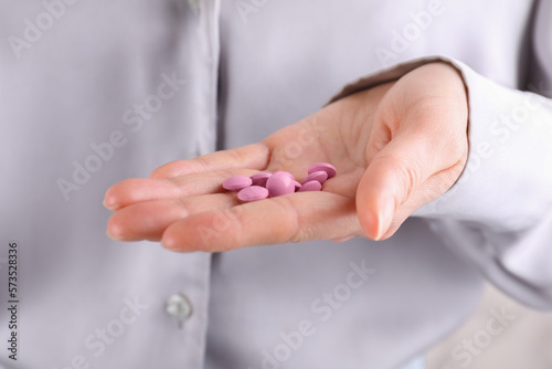 Woman holding pile of pink antidepressants, closeup view