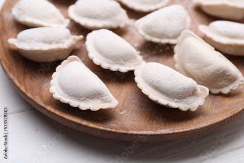 Raw dumplings (varenyky) on wooden plate, closeup