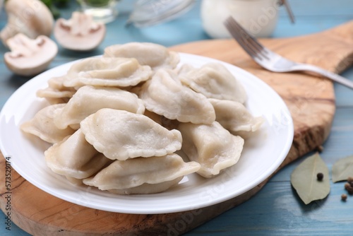 Delicious dumplings (varenyky) with potatoes served on light blue wooden table, closeup