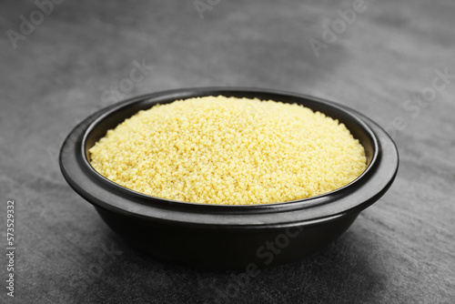 Bowl of raw couscous on grey table, closeup