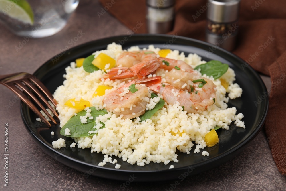 Tasty couscous with shrimps, bell pepper and basil on brown textured table, closeup Tasty couscous with shrimps, bell pepper and basil on brown textured table, closeup