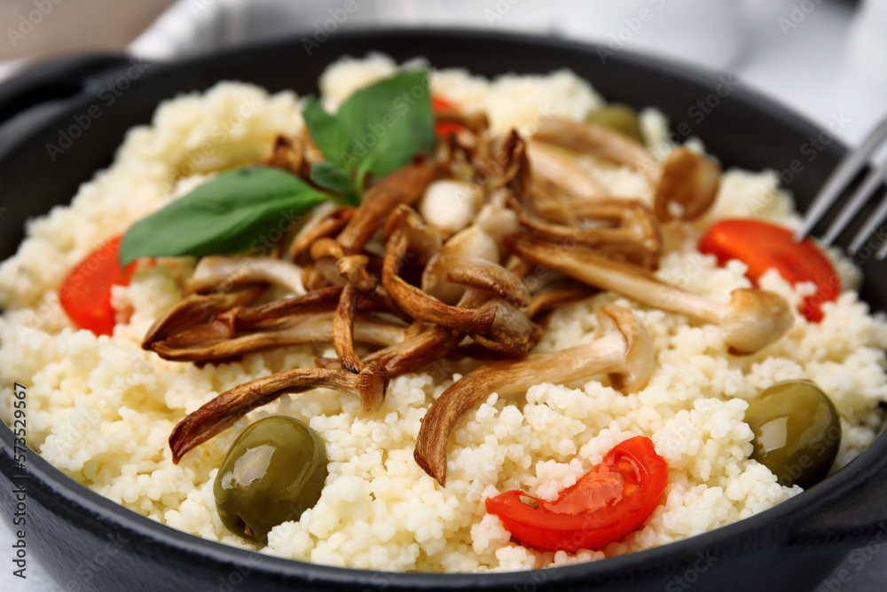 Tasty couscous with mushrooms, olives and tomatoes on table, closeup Tasty couscous with mushrooms, olives and tomatoes on table, closeup