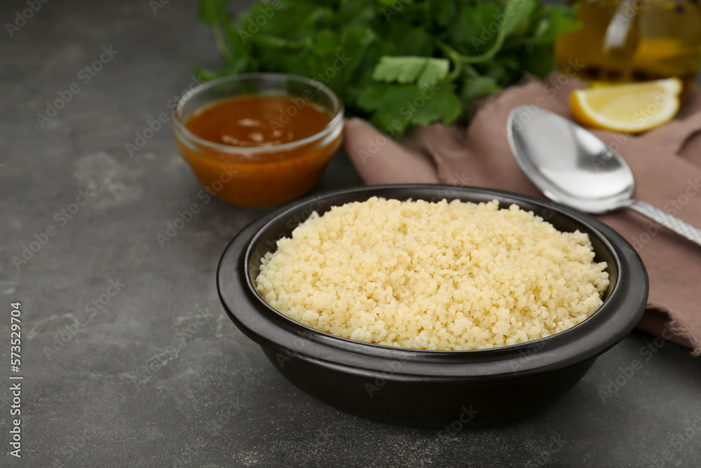 Bowl of tasty couscous on grey table, space for text Bowl of tasty couscous on grey table, space for text