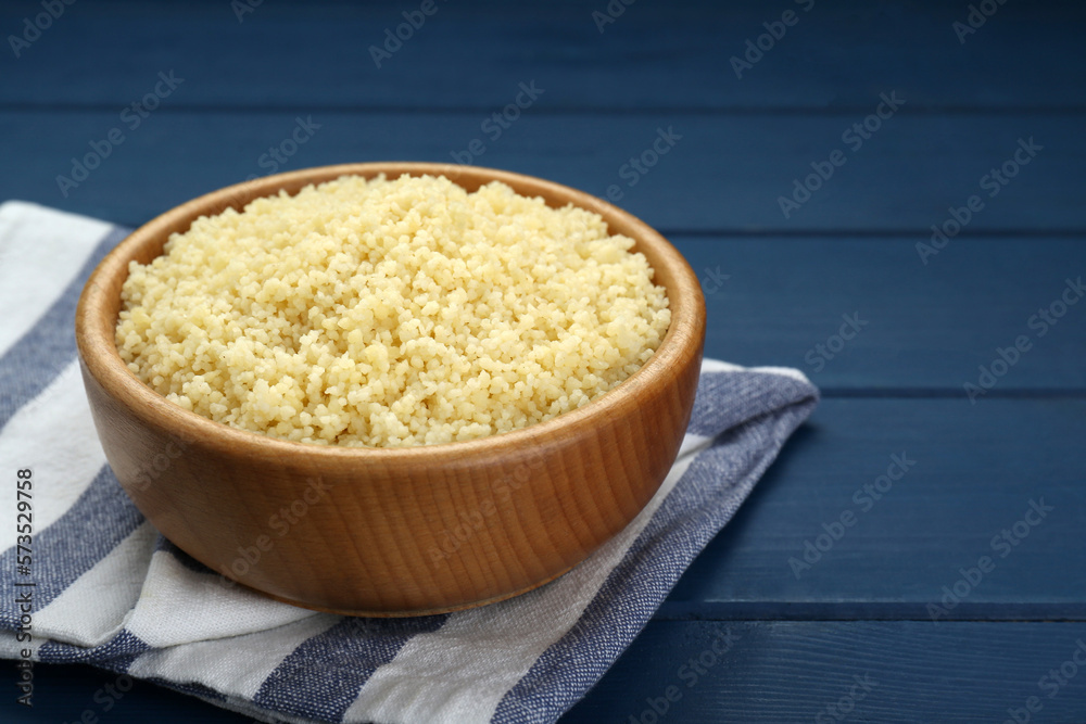 Bowl of tasty couscous on blue wooden table, closeup. Space for text Bowl of tasty couscous on blue wooden table, closeup. Space for text