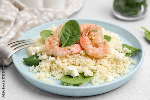 Delicious couscous with shrimps and spinach served on white table, closeup