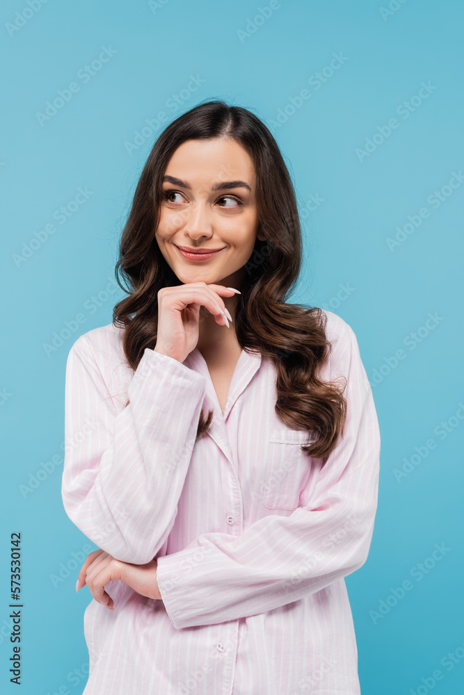smiling young woman in sleepwear looking away isolated on blue. smiling young woman in sleepwear looking away isolated on blue.