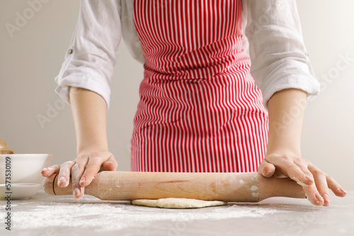 Woman rolling fresh dough at light grey table, closeup. Cooking grissini © New Africa