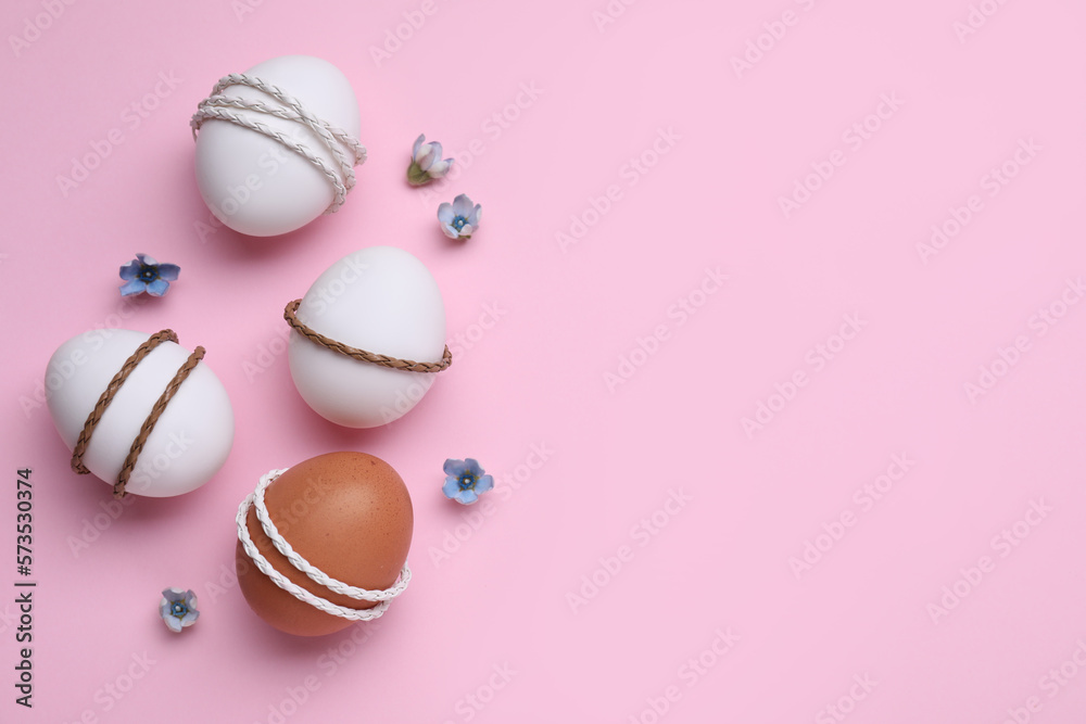 Beautifully decorated Easter eggs and flowers on pink background, flat lay. Space for text Beautifully decorated Easter eggs and flowers on pink background, flat lay. Space for text