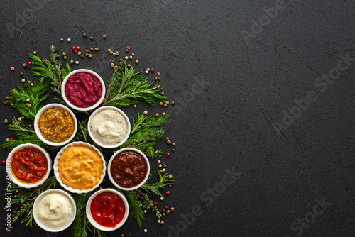 Fototapeta Naklejka Na Ścianę i Meble -  Different types of sauces in bowls with seasonings, rosemary and dill, thyme and and peppercorns, top view, copy space