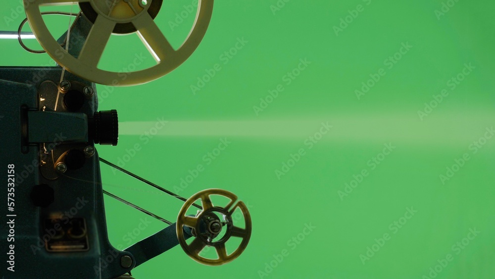 Silhouette detail hand turns on off vintage video projector on green screen