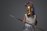 Shot of violent ancient female warrior with spear against grey background.