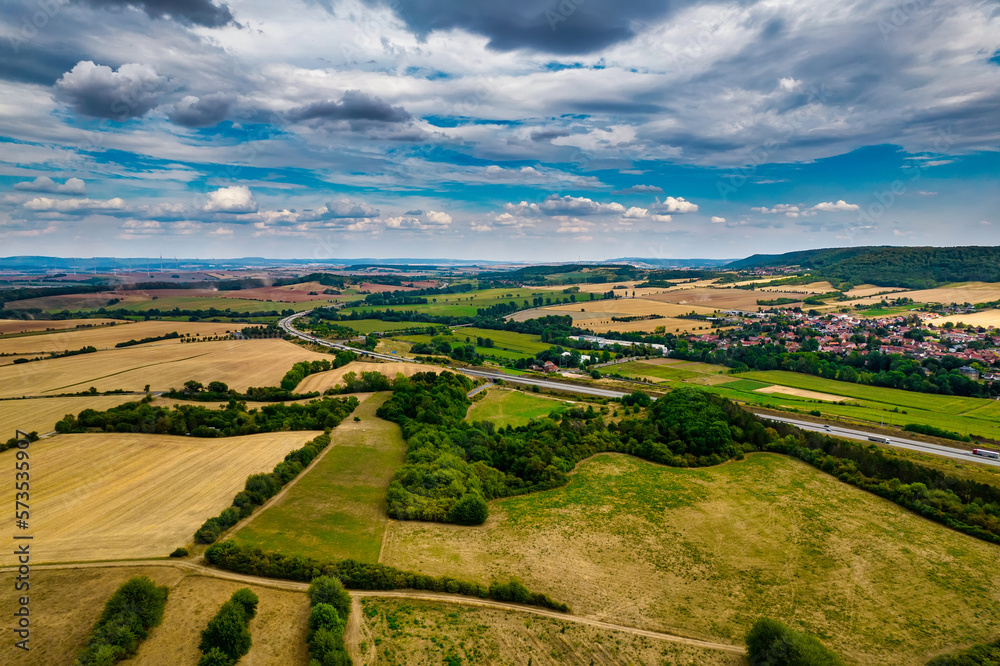 Aerial bird view of typical Ardennes green field meadows and hill landscape also showing highway and buildings in te far background of this german environment. Germany.