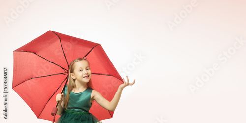 Portrait of a happy smiling child girl in green dress holding ambrella on pink background with space for text. photo