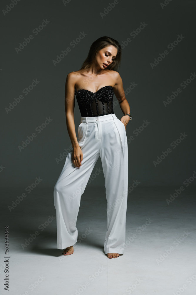 Sexy woman in black corset and black high boots. Fashion young woman with long legs posing at studio. Sexy woman in black corset and black high boots. Fashion young woman with long legs posing at studio.