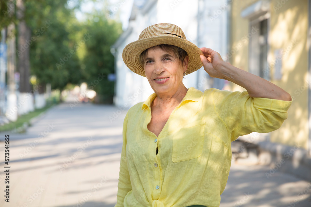 happy senior woman in sun hat walks  on summer city. 