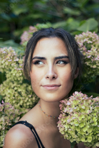 Young Italian brunette woman portrait between orthensia green flowers photo