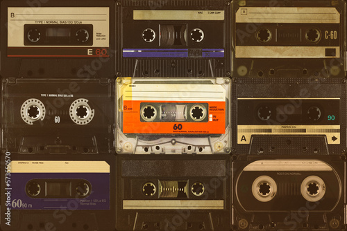 One vintage colorful orange compact cassette in front of black audio tapes