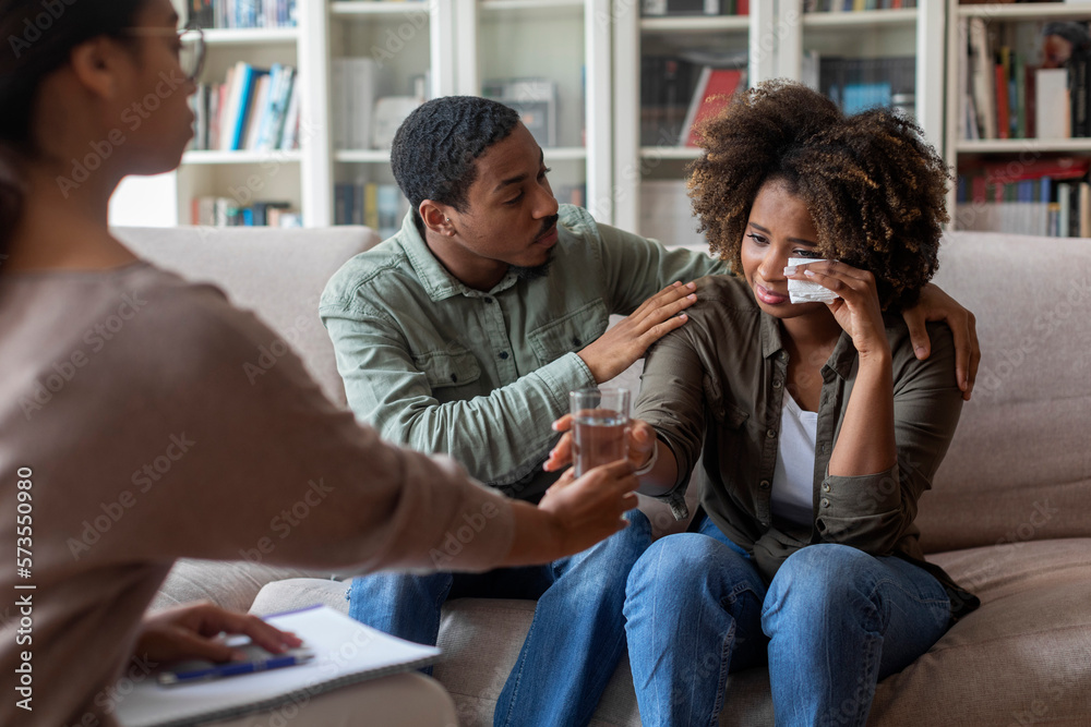 Loving african man comforting crying wife while having family therapy Loving african man comforting crying wife while having family therapy