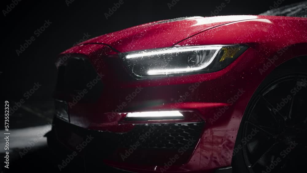 Close Up of a Modern Red Performance Car in a Dark Studio Environment. Creative Led Headlights Footage of a Performance Sportscar Dripping in Water After a Detailed Car Wash