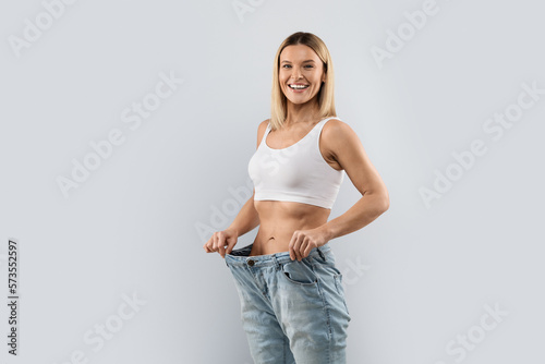 Happy middle aged woman wearing big jeans after weight loss
