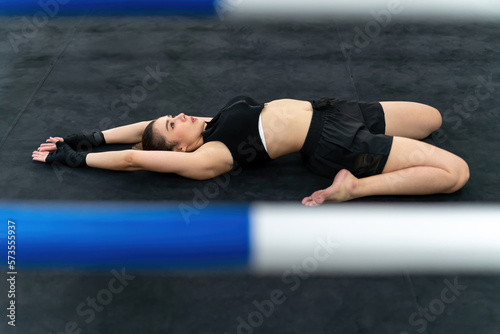 boxing woman wearing punching gloves bending body on ground. determined female athlete doing warm down or up. strong muscular gym trainer stretching bend body before exercise boxing sport training