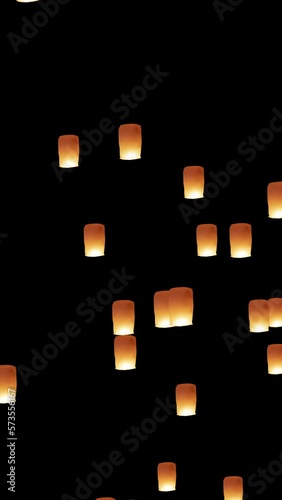 Chinese flying lanterns rising up in the night sky during holiday or festival. Computer generated animation. Seamless loopable vertical animation.