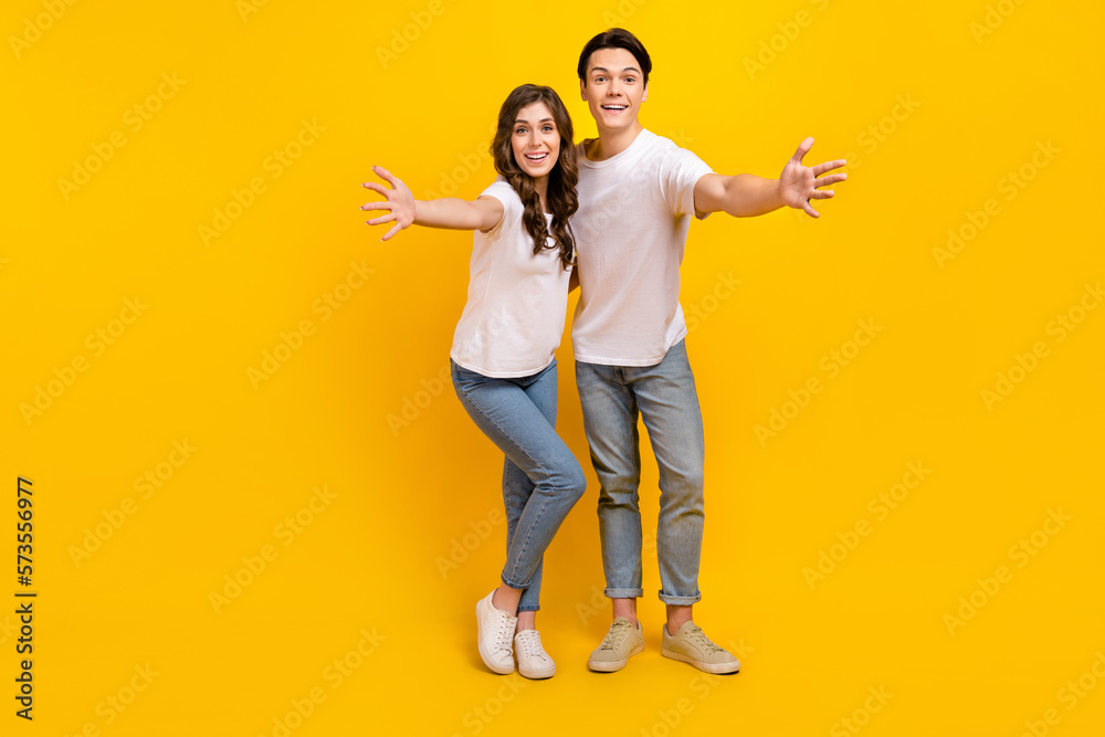 Fototapeta premium Full length photo of cute impressed husband wife dressed white t-shirts open arms empty space isolated yellow color background