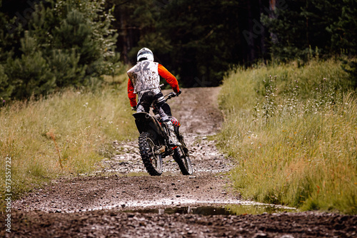 back enduro racer riding a dirty trail in motocross race