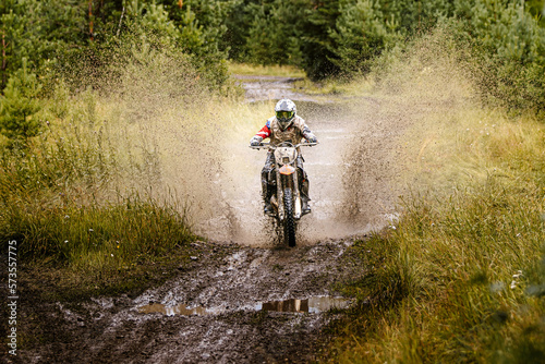 dirty motocross racer riding on mud and water in enduro race