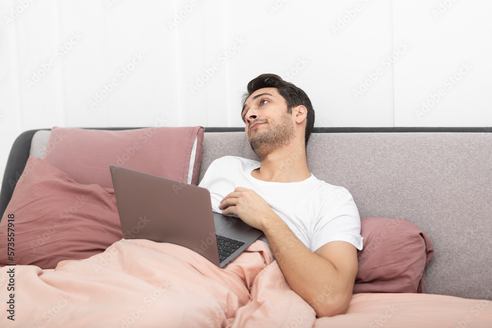 Lazy young handsome man sleeping on bed while working on laptop at home Lazy young handsome man sleeping on bed while working on laptop at home