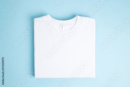 Leinwand Poster Basic folded white t-shirt blue background