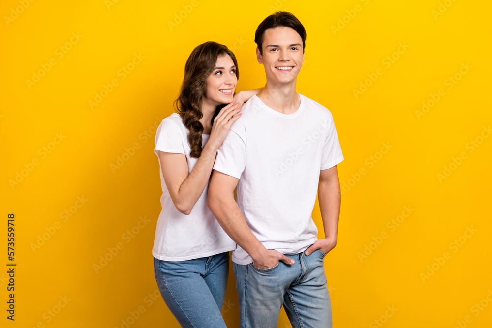 Photo portrait of young cheerful satisfied husband with wife wear white t-shirt touch shoulder look candid isolated on yellow color background Photo portrait of young cheerful satisfied husband with wife wear white t-shirt touch shoulder look candid isolated on yellow color background