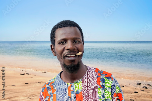 African man holding a miswak between his teeth at the beach (traditional teeth cleaning twig, also called sothio or sotio), photo photo
