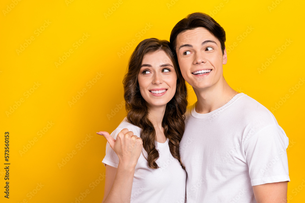 Photo of funny thoughtful husband wife dressed t-shirts looking pointing thumb back empty space isolated yellow color background Photo of funny thoughtful husband wife dressed t-shirts looking pointing thumb back empty space isolated yellow color background