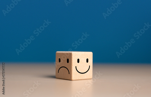 Emotional state and mental health concept, Smile face on bright side and sad face on dark side of wooden block cube for positive mindset selection.