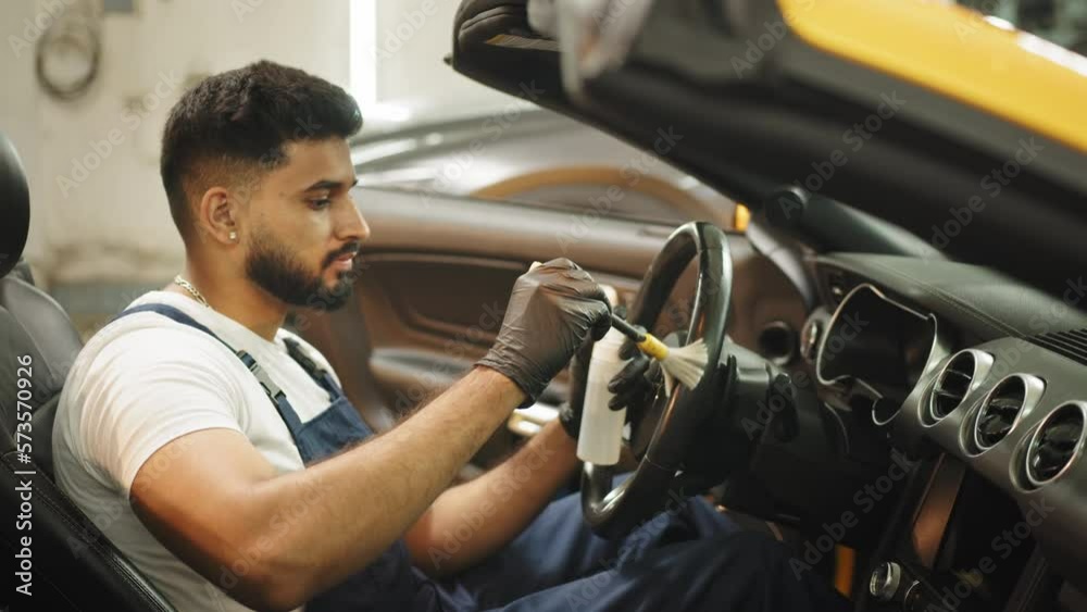 Car detailing and interior care concept. Young man, car wash worker, wearing protective rubber