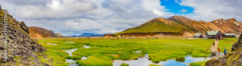 Panoramic Icelandic landscape of colorful rainbow volcanic Landmannalaugar mountains, at Laugavegur hiking trail with dramatic sky, colorful rhyolite volcano, campsite and lava fields in Iceland.