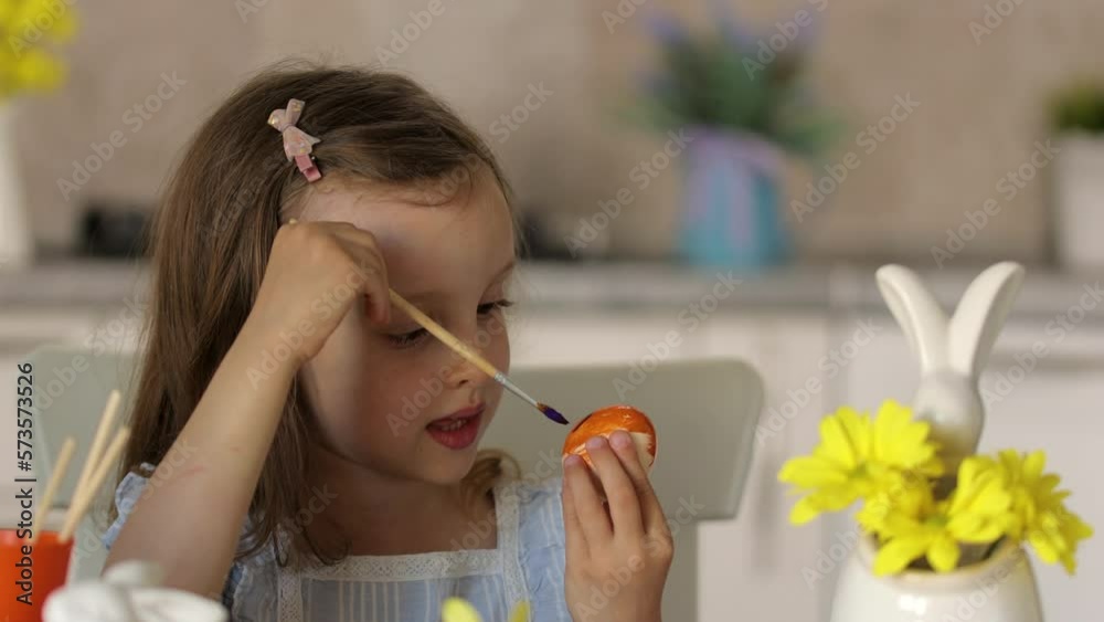a girl shows a decorated egg for the Easter holiday, sitting at a table a girl shows a decorated egg for the Easter holiday, sitting at a table